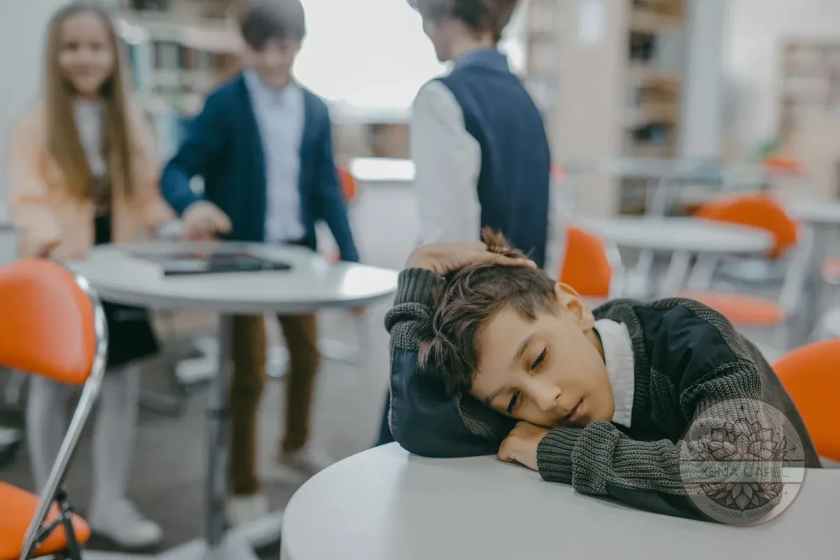 Assetjament escolar: nen trist i aïllat a l'aula mentre els companys interactuen al fons, exclusió i bullying
