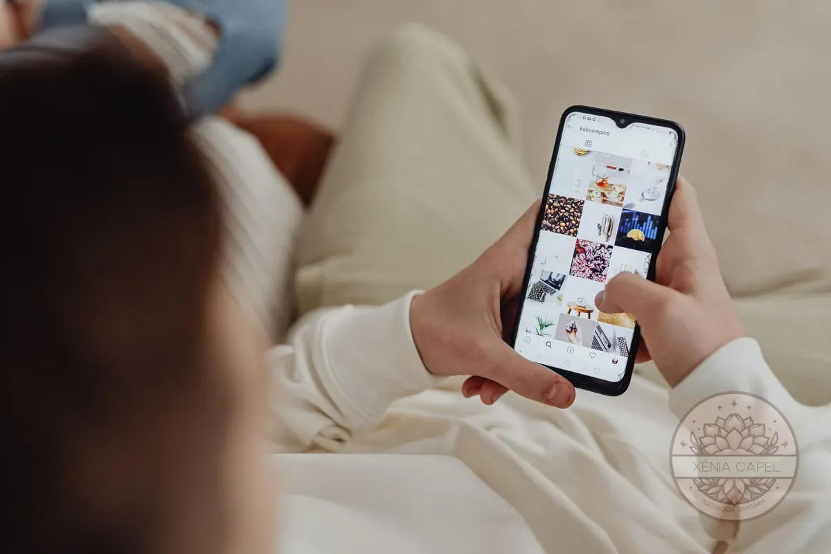 Adicción al móvil: persona en el sofá absorta desplazándose por las redes sociales en el smartphone