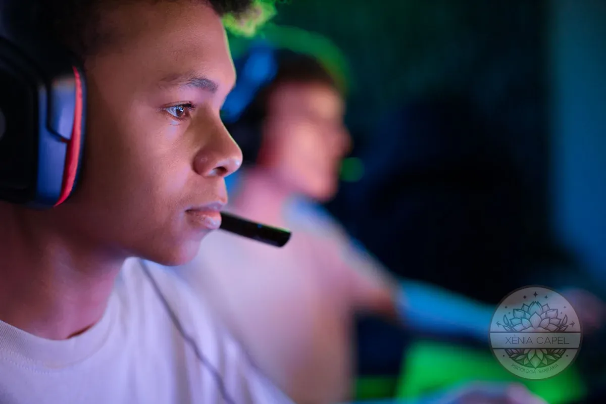 Adicción a los videojuegos: un adolescente con auriculares absorto en una partida de noche, iluminado por la pantalla
