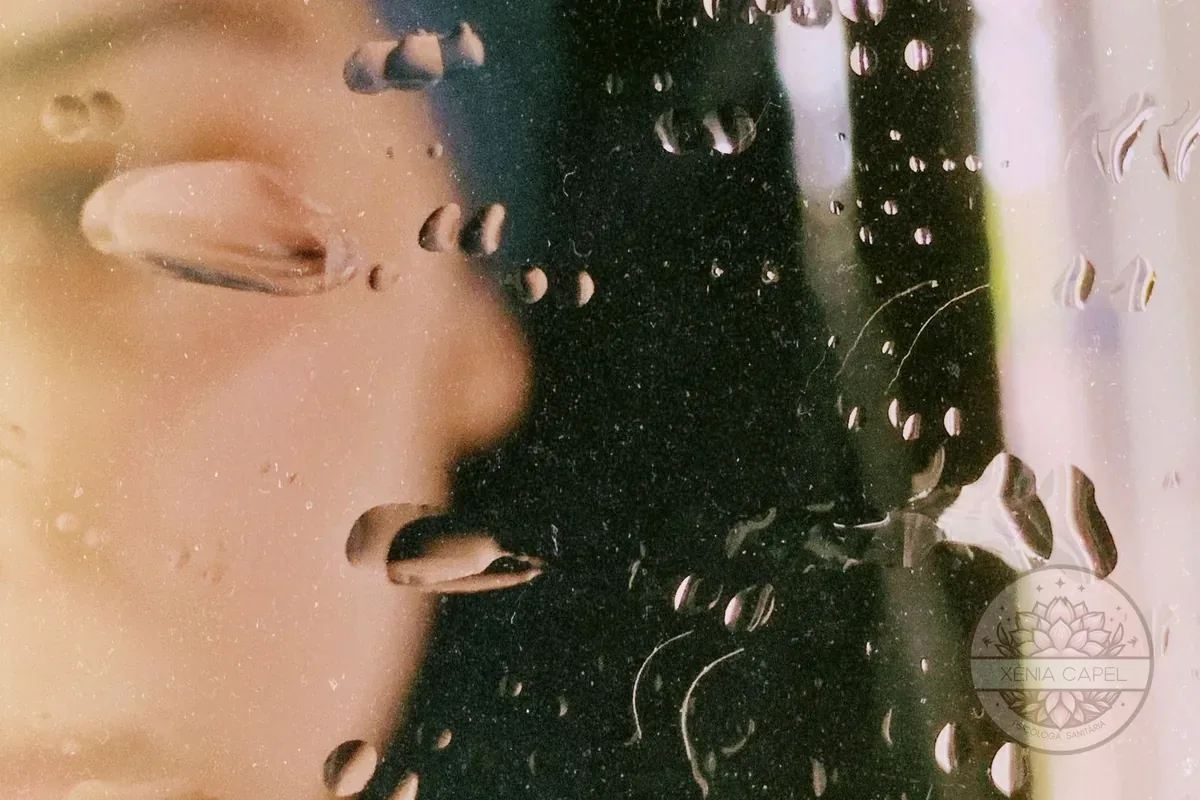 Despersonalización y desrealización: rostro difuminado detrás de un cristal cubierto de lluvia, una imagen de la sensación de irrealidad y desconexión