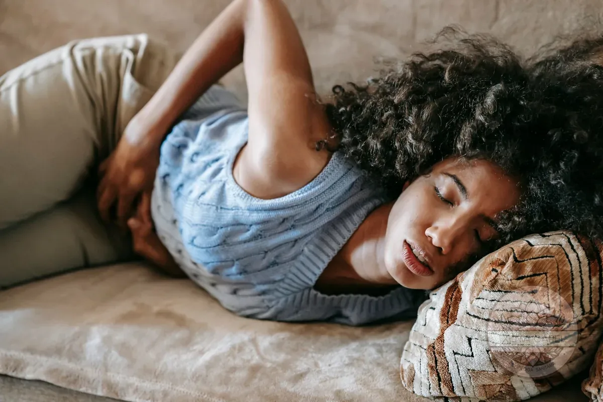Emetofobia: una mujer en el sofá con la mano en el estómago y sensación de náusea y angustia