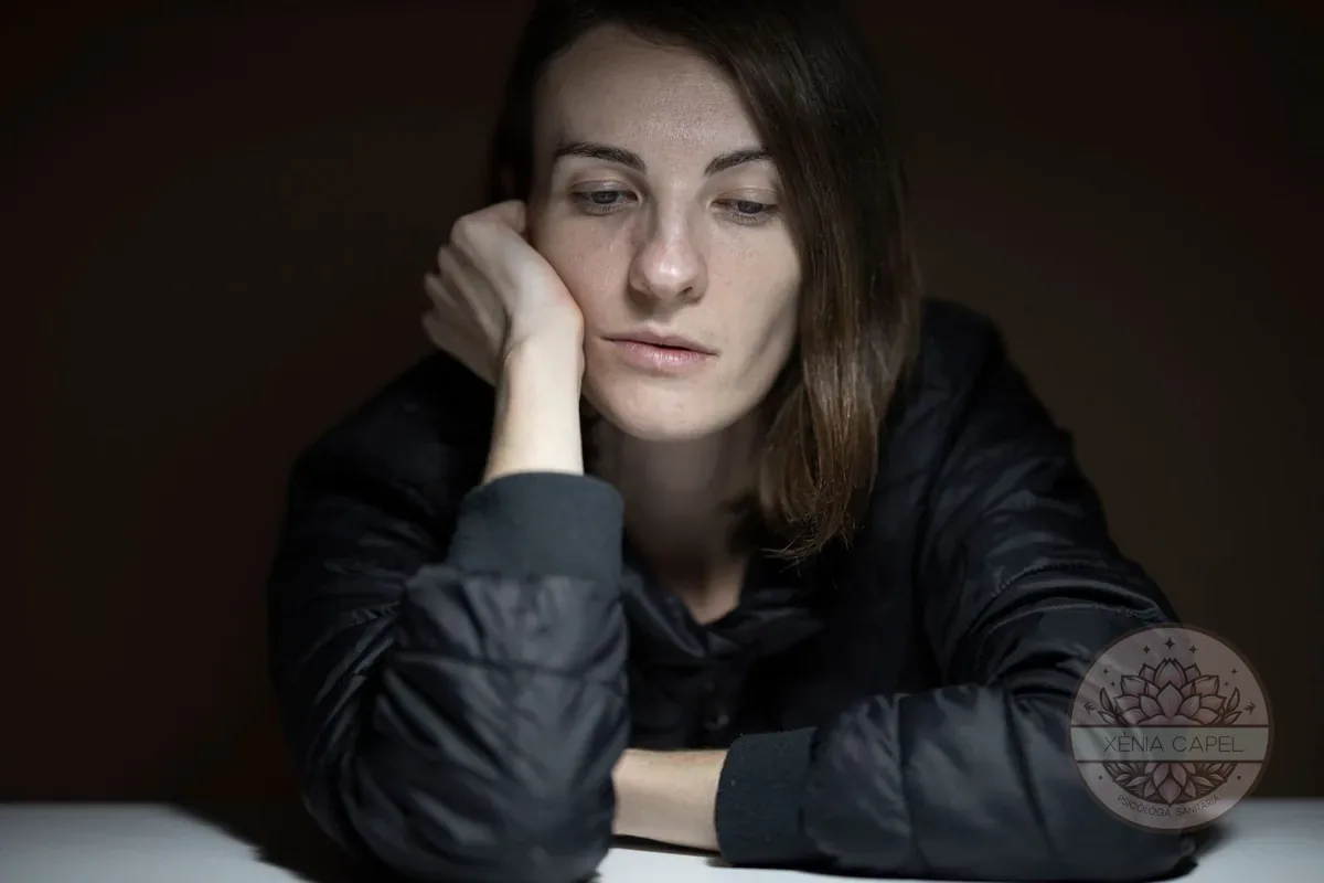 Gaslighting: a thoughtful, worn-down woman with her hand on her cheek, doubting herself in low light