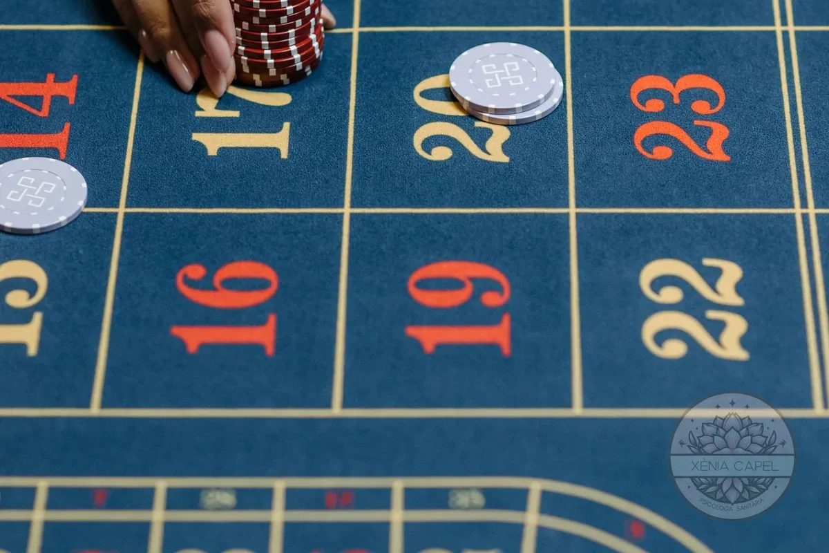 Ludopatía: mano apostando fichas sobre una mesa de ruleta, símbolo de la adicción al juego