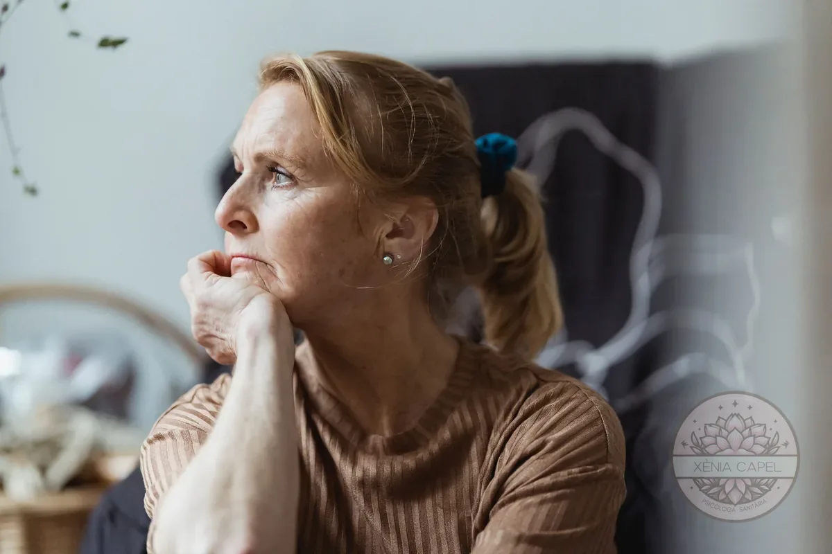 Síndrome del niu buit: dona madura pensativa a casa amb la mà a la barbeta, enyorant els fills que han marxat