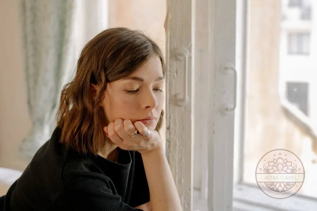 Premenstrual syndrome: a pensive, low-mood woman leaning by a window, emotional symptoms before the period
