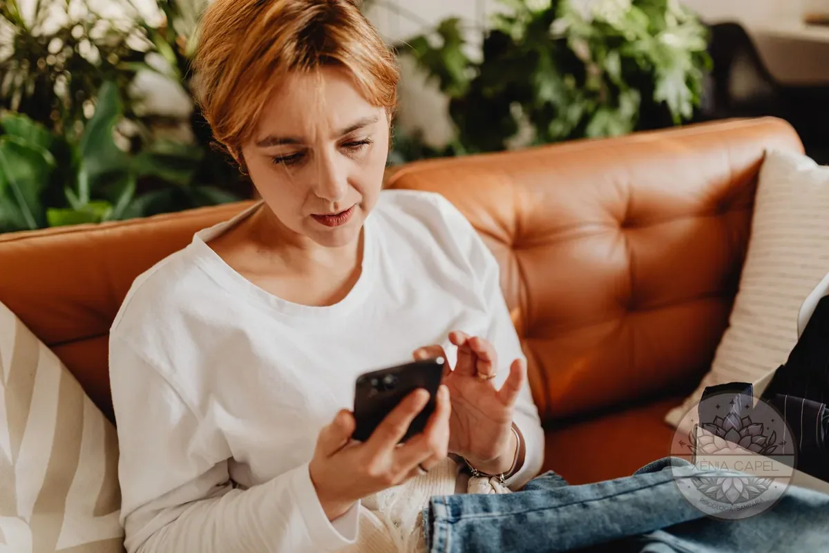 Mujer haciendo un test psicológico online en el móvil, tranquila en el sofá de casa