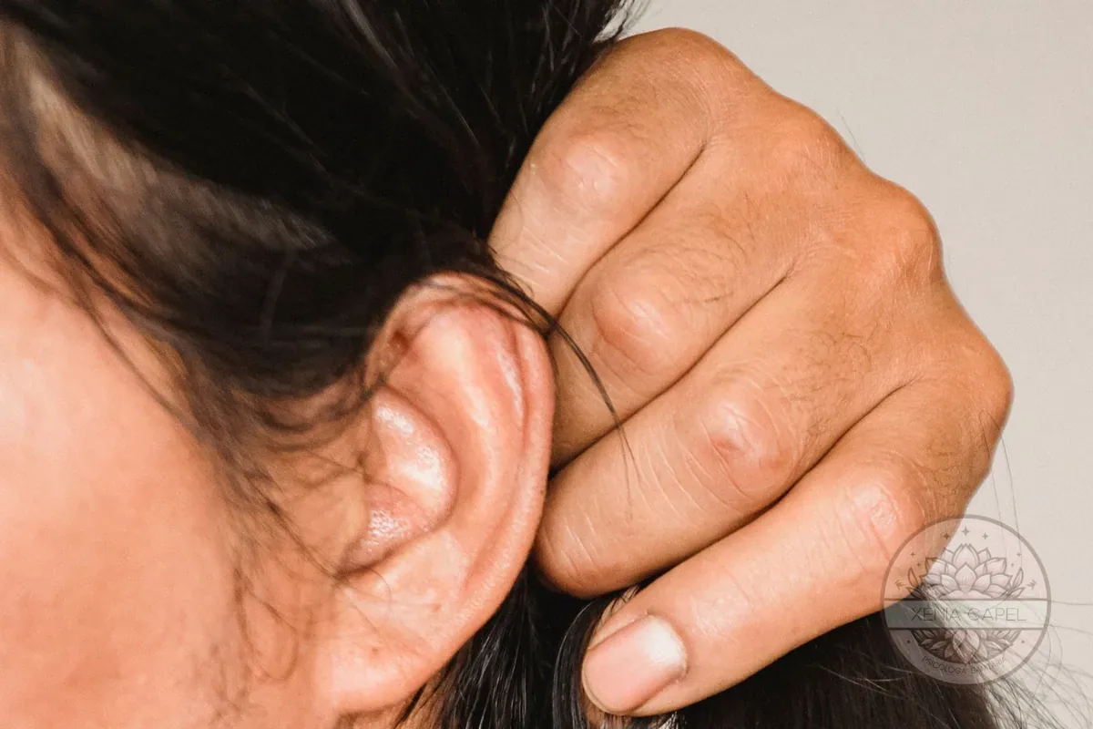 Tricotilomanía: primer plano de una mano que agarra y tira de un mechón de pelo junto a la oreja